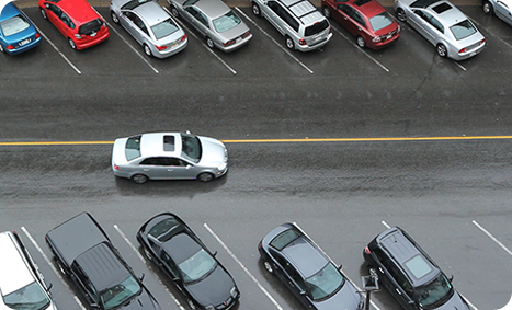 Orbit Creative video still of overhead view of silver car driving past parked cars on wet and rainy street